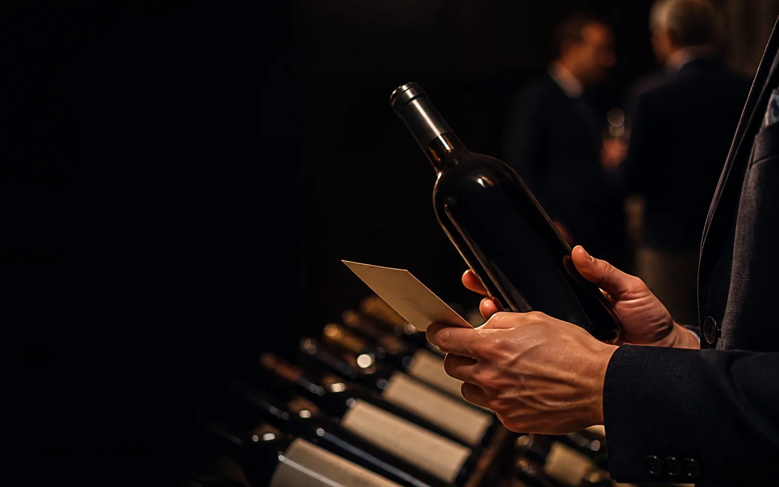A collector inspecting an unbranded bottle at a wine auction preview